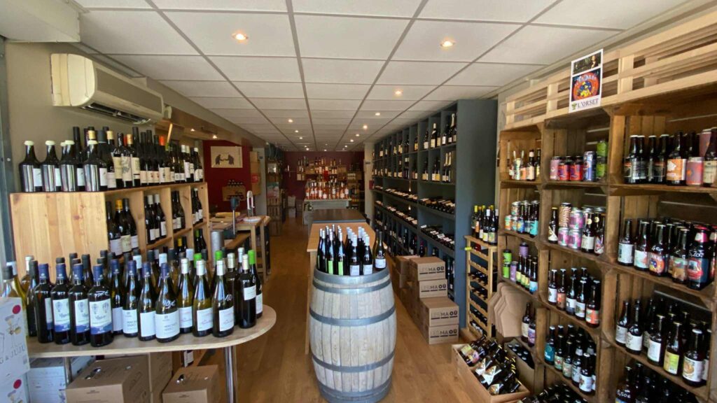 Boutique de Vins et Bières Artisanales : Cave et Terroir Boutique de vins et bières artisanales avec étagères en bois, tonneau central et cartons de vin Les Maou.