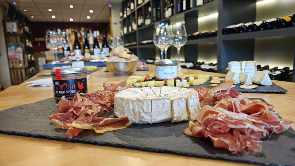 Plateau Charcuterie et Fromage : Dégustation en Cave à Vin Planche de charcuterie, camembert et pâté de volaille au piment d'Espelette servie dans une cave à vin gourmande.