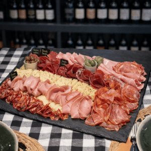 Planche de charcuterie et fromage garnie de jambon, salami et olives sur une table de bar à vin.