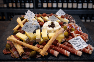 Assortiment de fromages Comté, charcuterie Jambon de Cebo et olives sur un plateau d'ardoise rustique.