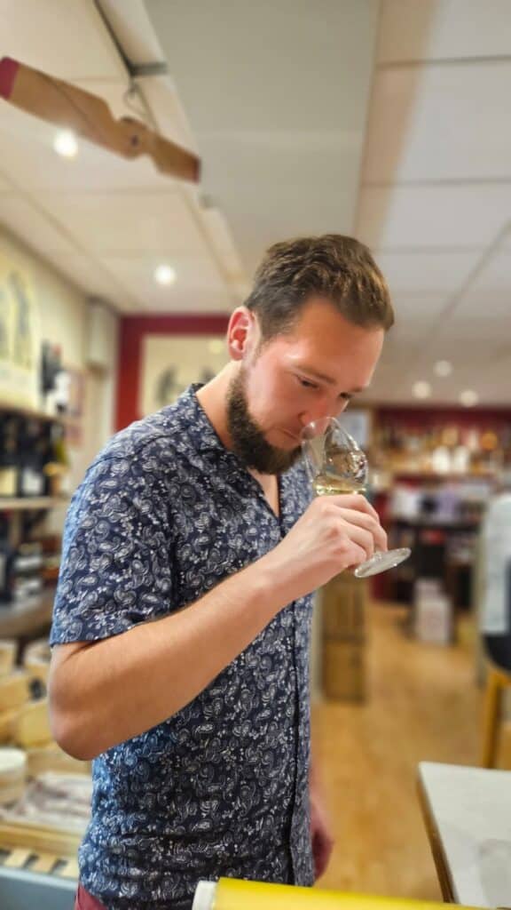 Dégustation de Vin Blanc par un Homme Passionné Homme barbu en chemise paisley sentant un verre de vin blanc lors d'une dégustation dans une cave.