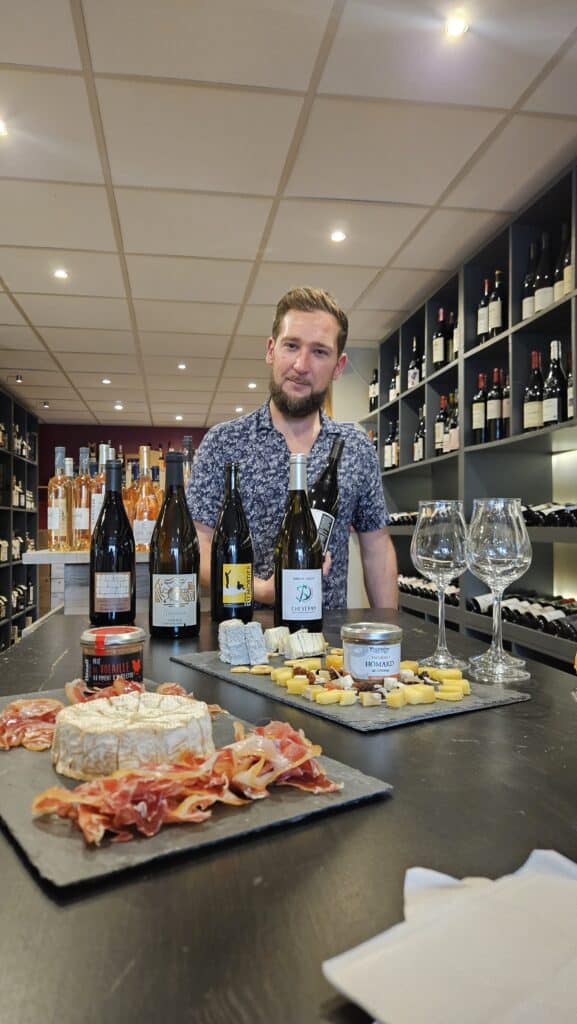 Dégustation de Vins de Loire et Fromages avec un Caviste Caviste souriant présentant vins de Loire (Cheverny), fromages et charcuterie pour une séance de dégustation conviviale.
